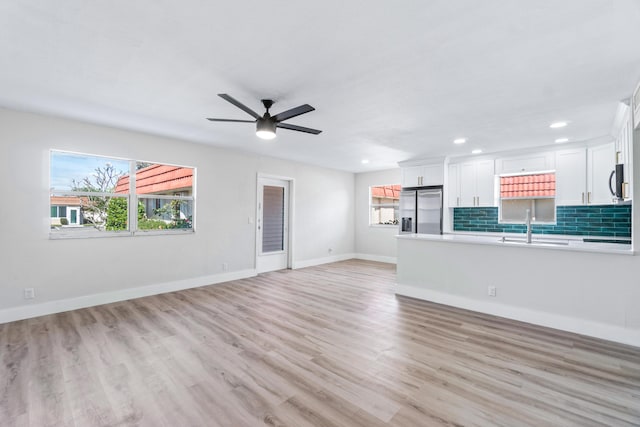 unfurnished living room featuring ceiling fan, light wood-type flooring, and sink