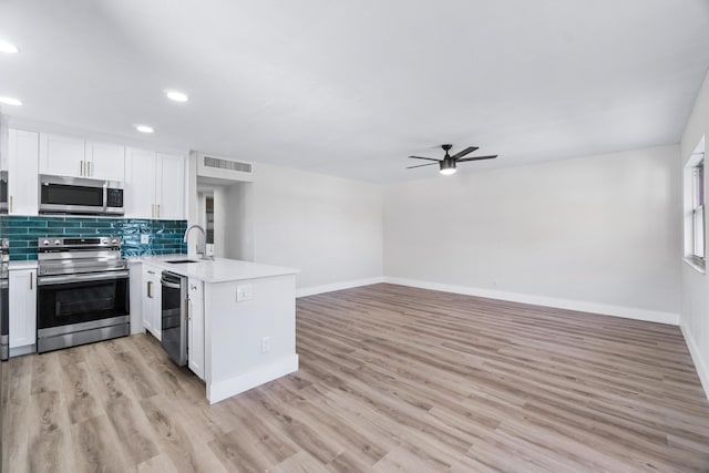 kitchen featuring stainless steel appliances, kitchen peninsula, ceiling fan, sink, and white cabinetry