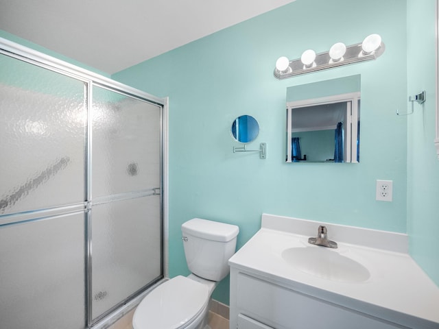 bathroom featuring vanity, toilet, and a shower with door