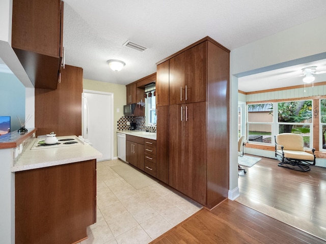 kitchen with sink, backsplash, white dishwasher, light hardwood / wood-style floors, and a textured ceiling