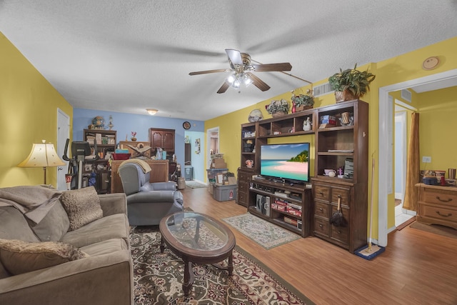 living room featuring ceiling fan, hardwood / wood-style floors, and a textured ceiling