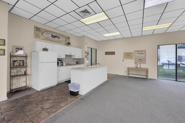 kitchen featuring sink, a center island, dark carpet, white fridge, and white cabinets