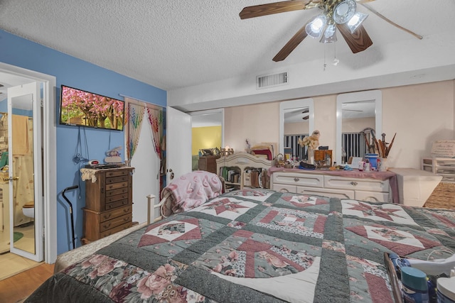 bedroom featuring hardwood / wood-style flooring, a textured ceiling, ceiling fan, and ensuite bath