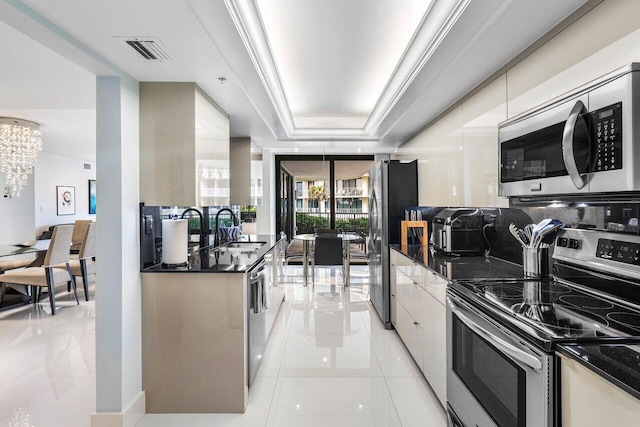 kitchen with a notable chandelier, a raised ceiling, sink, light tile patterned flooring, and stainless steel appliances