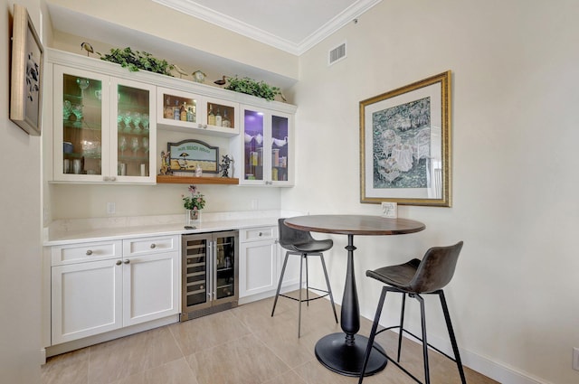 bar featuring light tile patterned floors, white cabinetry, crown molding, and wine cooler