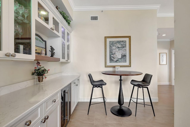 bar featuring white cabinets, light stone counters, beverage cooler, and ornamental molding