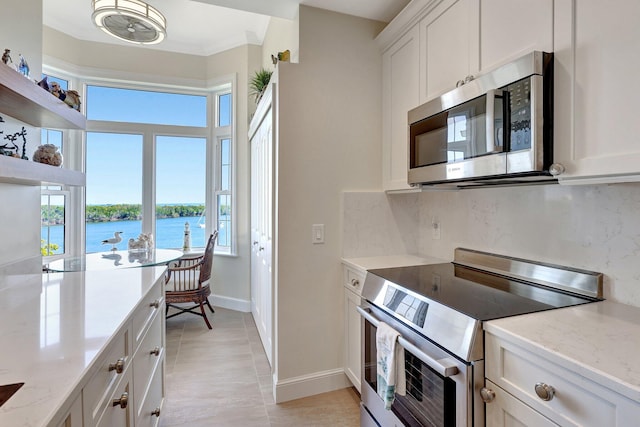 kitchen with white cabinets, a water view, light stone countertops, and stainless steel appliances