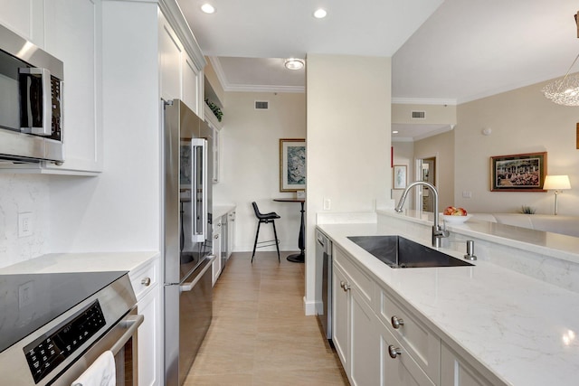 kitchen with appliances with stainless steel finishes, light stone counters, sink, decorative light fixtures, and white cabinets