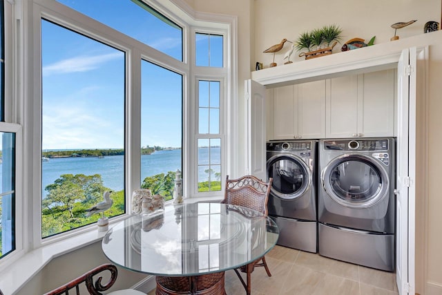 laundry room with cabinets, a water view, washer and clothes dryer, and light tile patterned flooring