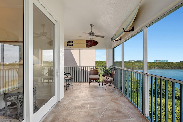 sunroom featuring ceiling fan and a water view