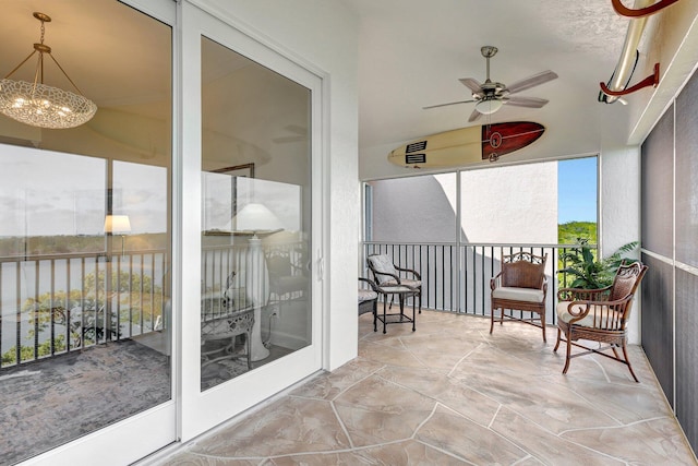 sunroom featuring ceiling fan with notable chandelier