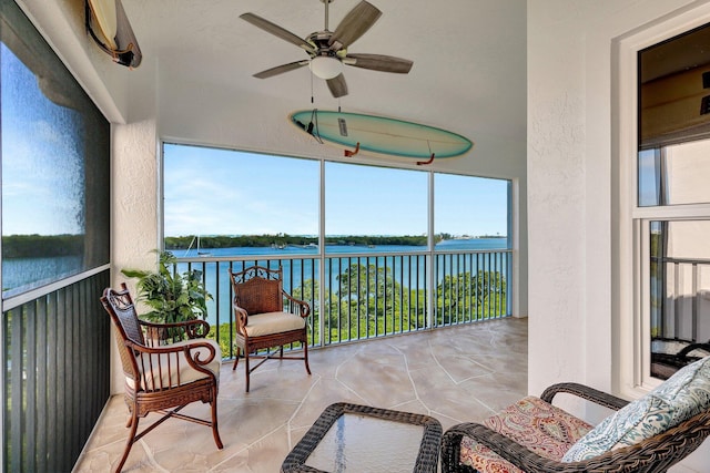 sunroom / solarium featuring ceiling fan and a water view