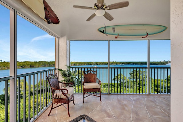 sunroom / solarium with ceiling fan and a water view