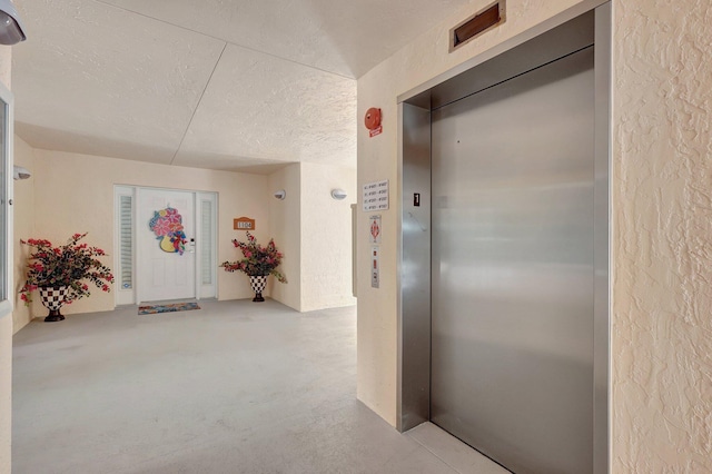 hallway with a textured ceiling and elevator