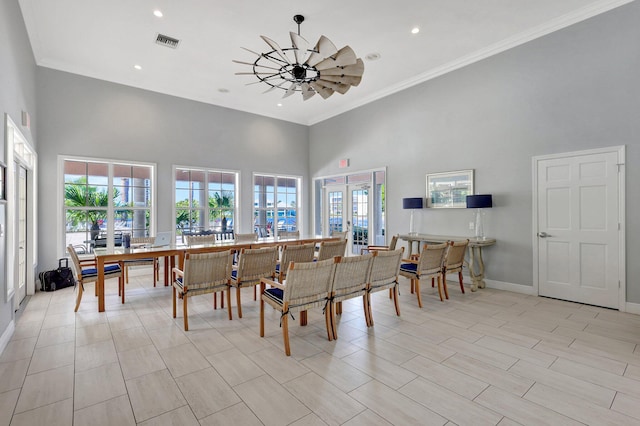 dining room featuring french doors, a towering ceiling, plenty of natural light, and ornamental molding