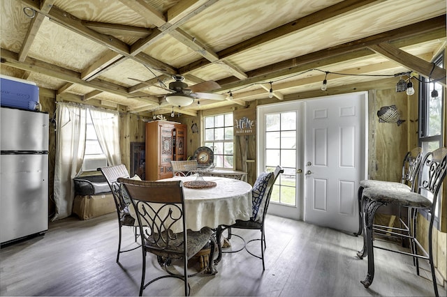 dining space with ceiling fan, wooden walls, and light hardwood / wood-style flooring