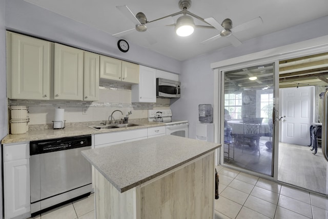 kitchen featuring ceiling fan, sink, light tile patterned flooring, a kitchen island, and appliances with stainless steel finishes