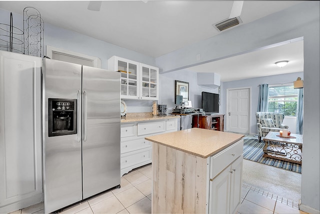 kitchen featuring white cabinets, stainless steel fridge, a kitchen island, and light tile patterned flooring