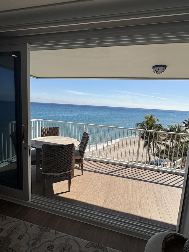 balcony with a water view and a view of the beach