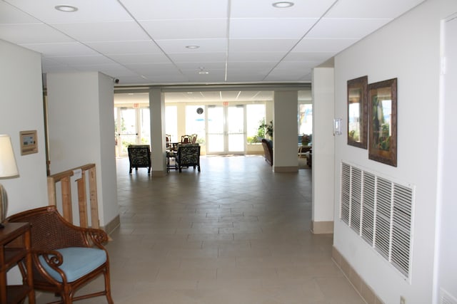 hall featuring french doors, expansive windows, a healthy amount of sunlight, and a drop ceiling