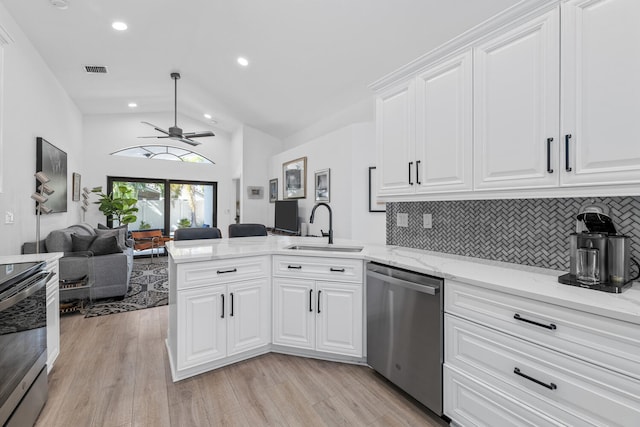 kitchen featuring kitchen peninsula, appliances with stainless steel finishes, decorative backsplash, sink, and white cabinets