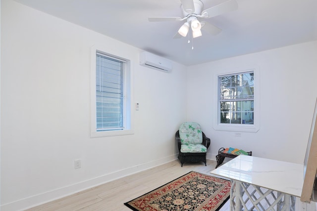 office area featuring a wall mounted AC, ceiling fan, and light hardwood / wood-style floors