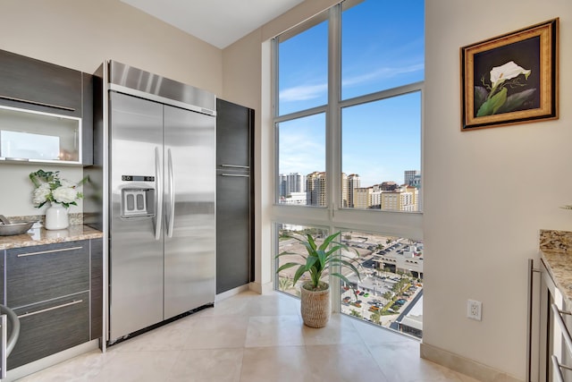 kitchen featuring built in fridge, light tile patterned flooring, and light stone countertops