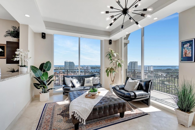 living room with a tray ceiling, floor to ceiling windows, and an inviting chandelier