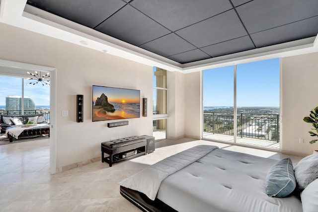 bedroom featuring access to outside, a wall of windows, a tray ceiling, and a notable chandelier