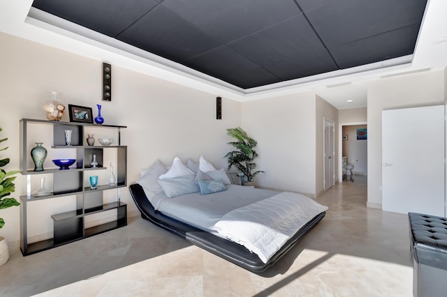 bedroom with concrete flooring and a raised ceiling