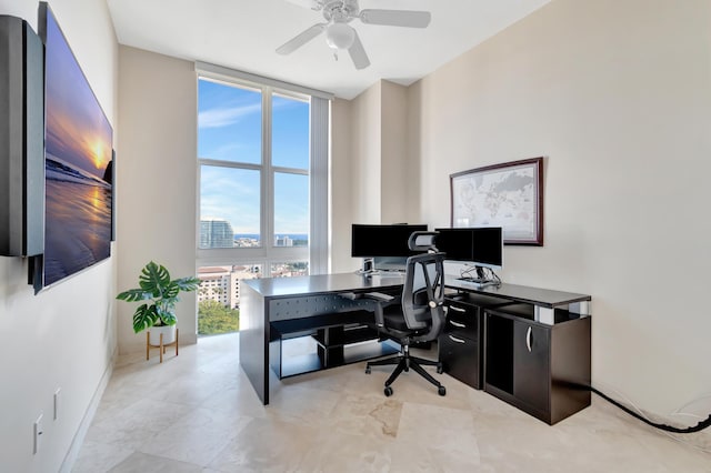 office space with ceiling fan, plenty of natural light, and a wall of windows