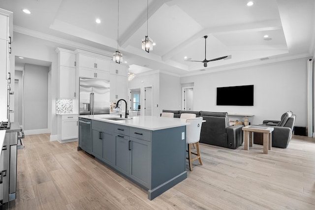 kitchen with sink, decorative light fixtures, an island with sink, stainless steel appliances, and white cabinets