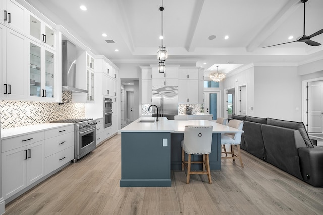 kitchen with white cabinetry, decorative light fixtures, premium appliances, and wall chimney exhaust hood