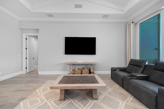 living room with crown molding, a tray ceiling, and light hardwood / wood-style floors