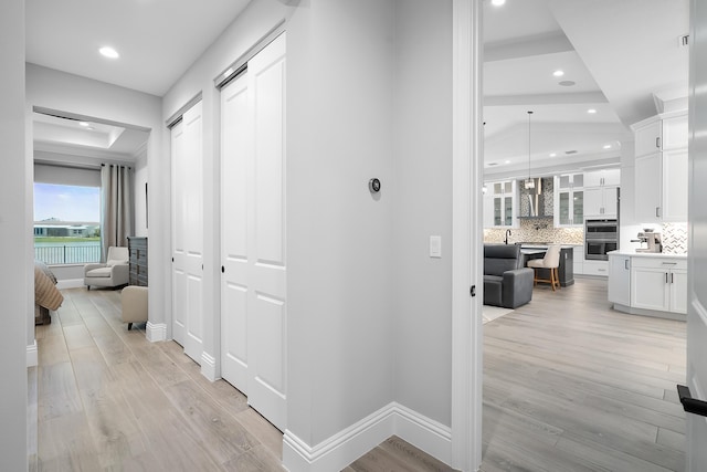 hall featuring a tray ceiling and light hardwood / wood-style flooring