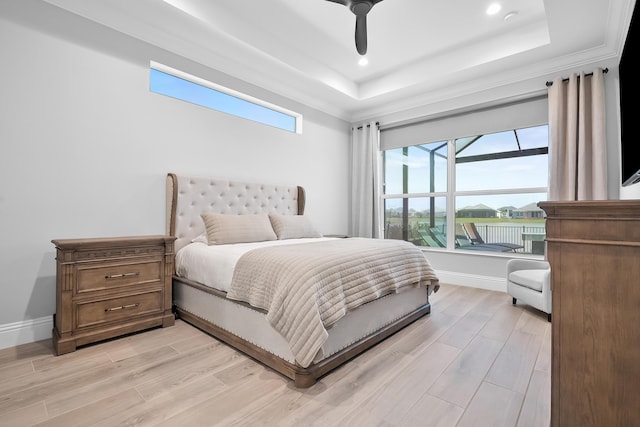 bedroom with a raised ceiling, ceiling fan, and light wood-type flooring