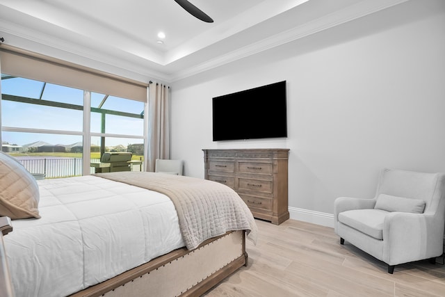 bedroom featuring ceiling fan, ornamental molding, a raised ceiling, and light wood-type flooring