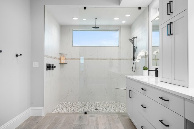 bathroom with a tile shower, vanity, and hardwood / wood-style flooring