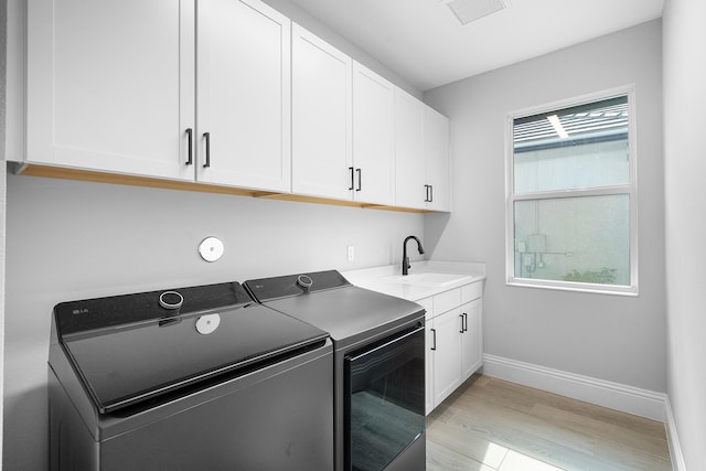 washroom featuring cabinets, a healthy amount of sunlight, sink, and washer and dryer