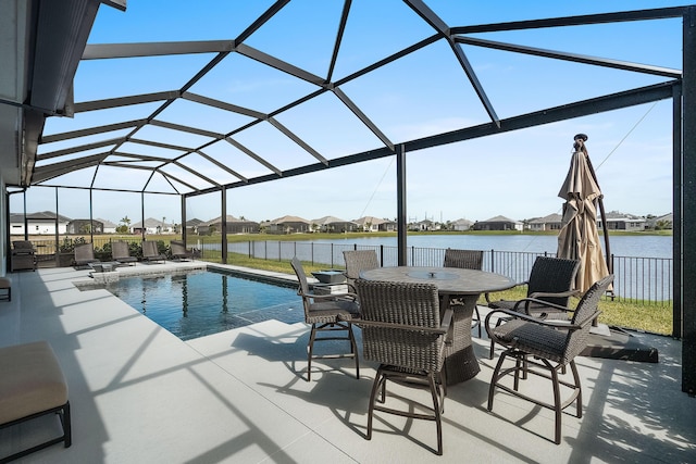 view of pool featuring a patio area, a water view, and glass enclosure