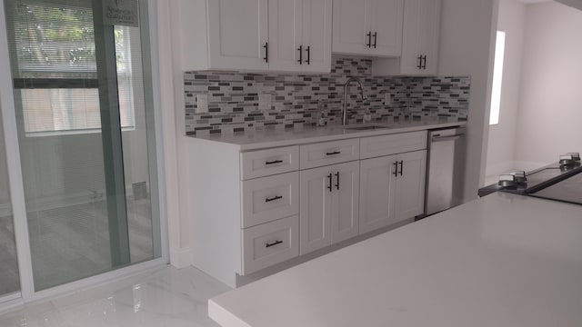 kitchen featuring white cabinets, sink, stainless steel dishwasher, decorative backsplash, and a wealth of natural light