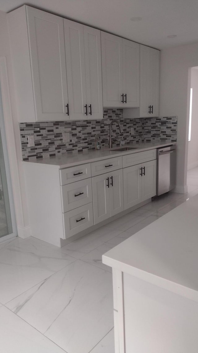 kitchen featuring dishwasher, backsplash, white cabinetry, and sink