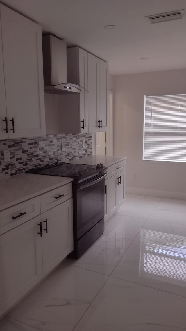 kitchen featuring white cabinets, backsplash, electric stove, and wall chimney range hood