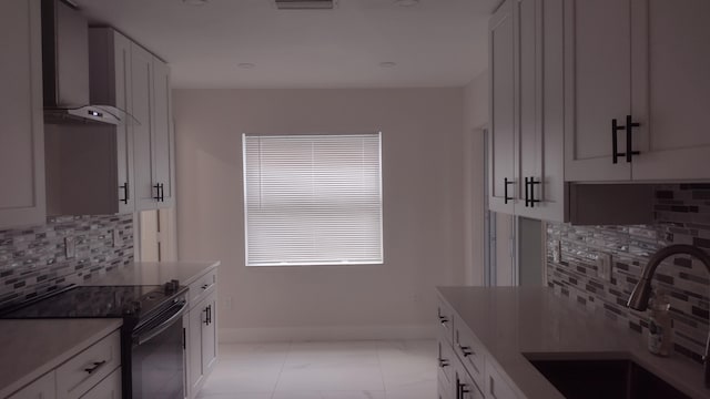 kitchen featuring sink, black range with electric cooktop, white cabinetry, and wall chimney range hood