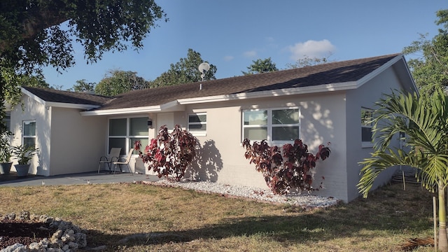 ranch-style home with a front lawn and a patio