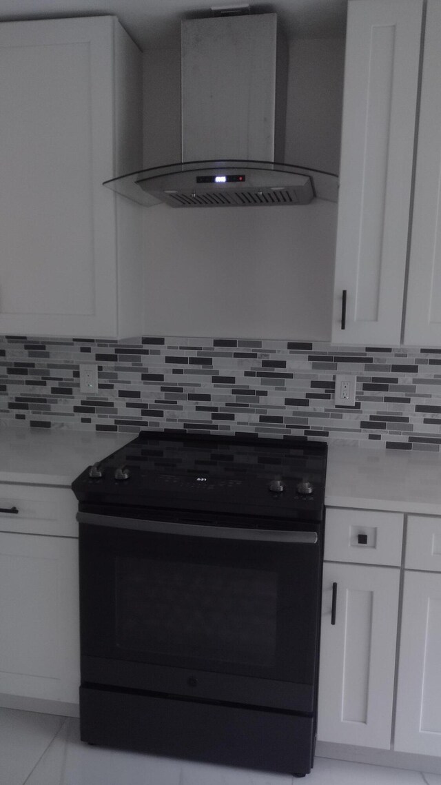 kitchen with white cabinets, decorative backsplash, wall chimney range hood, and black electric range