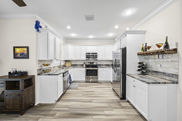 kitchen with tasteful backsplash, white cabinets, sink, and stainless steel appliances