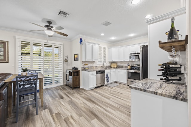 kitchen with light stone countertops, appliances with stainless steel finishes, white cabinetry, decorative backsplash, and sink