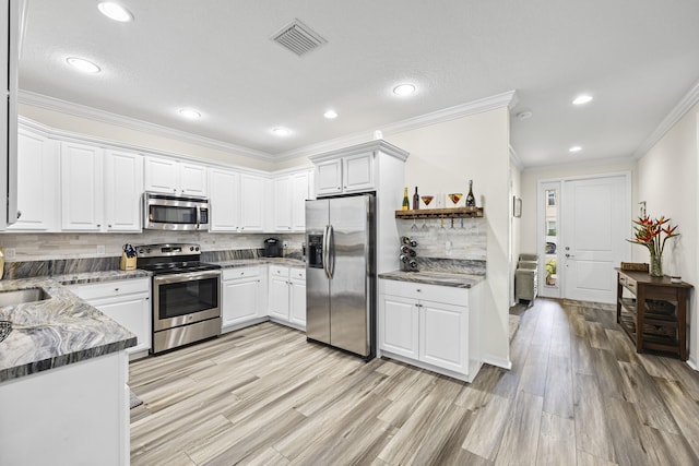 kitchen with light hardwood / wood-style floors, white cabinets, stainless steel appliances, and tasteful backsplash