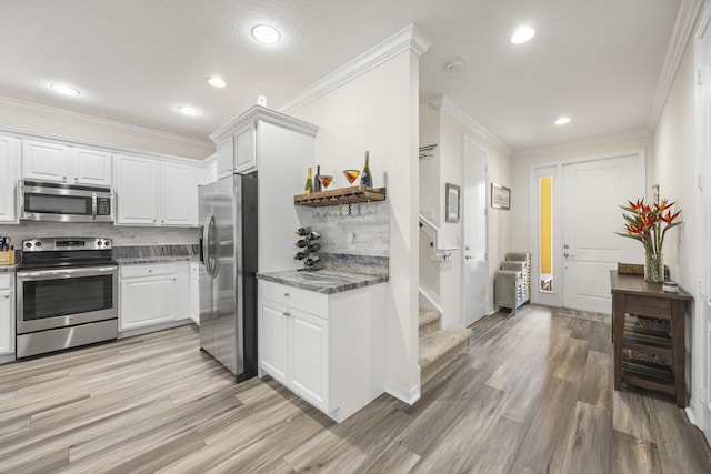 kitchen with stainless steel appliances, light hardwood / wood-style flooring, white cabinetry, and tasteful backsplash